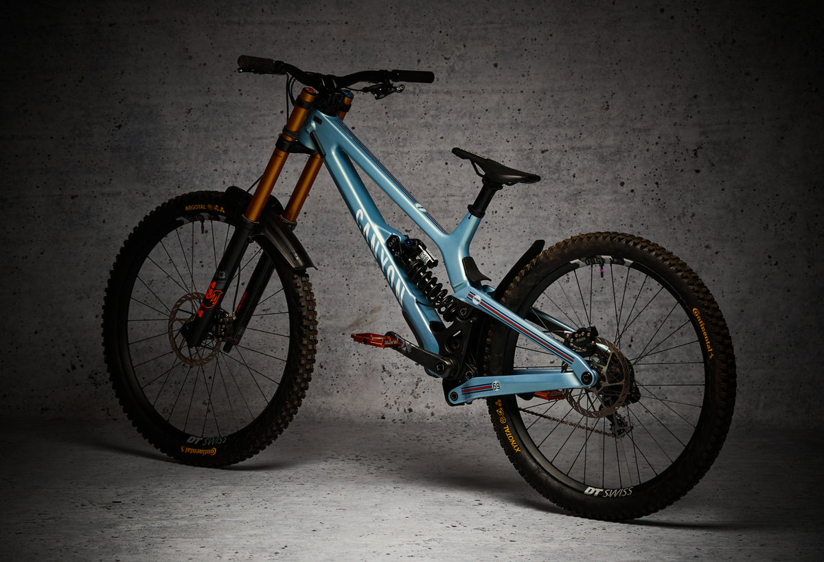 Bici de descenso azul claro con un protector NEO Racing, vista en tres cuartos